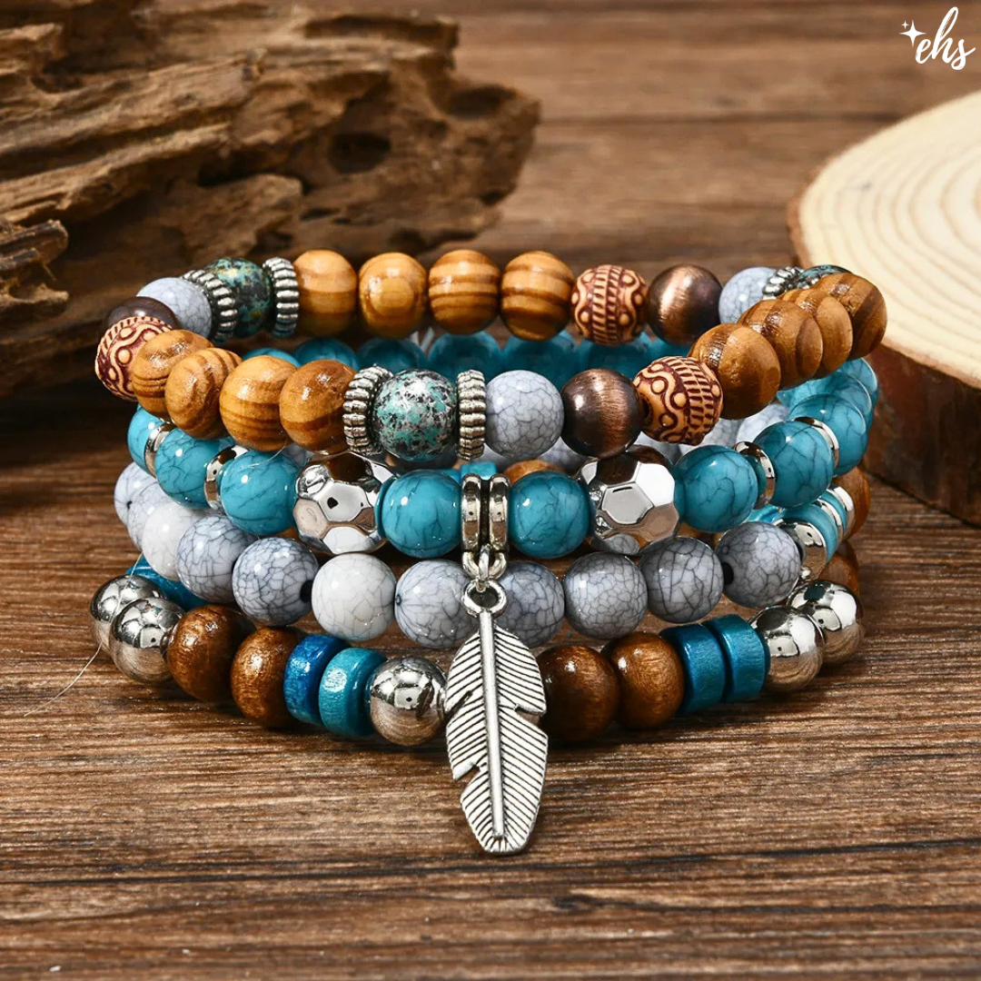 A stack of beaded bracelets with turquoise, blue, brown, and gray marbled beads, silver spacer beads, and a silver feather charm, displayed on a rustic wooden surface.
