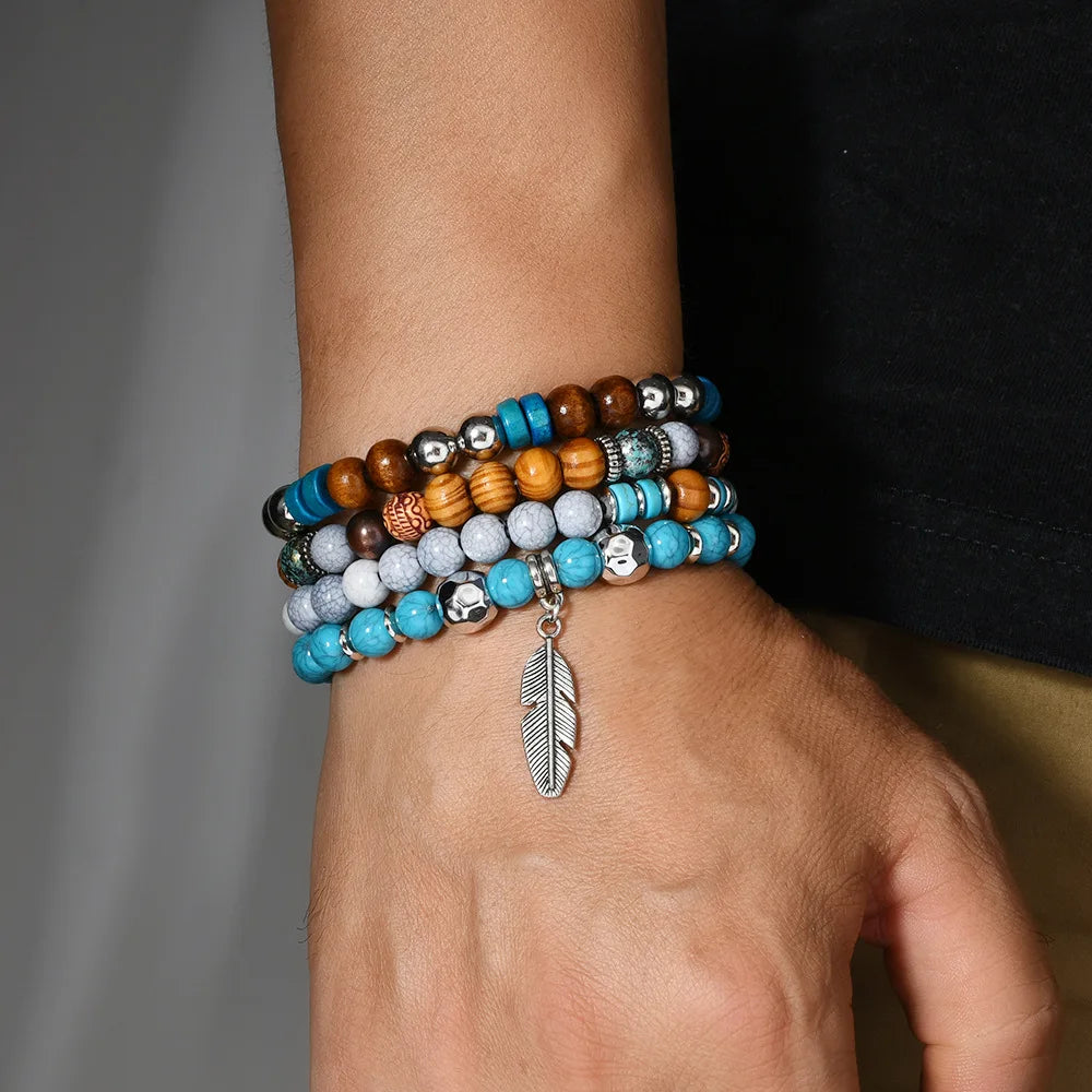 Multicolored beaded bracelet with a feather charm on a wrist against a neutral background
